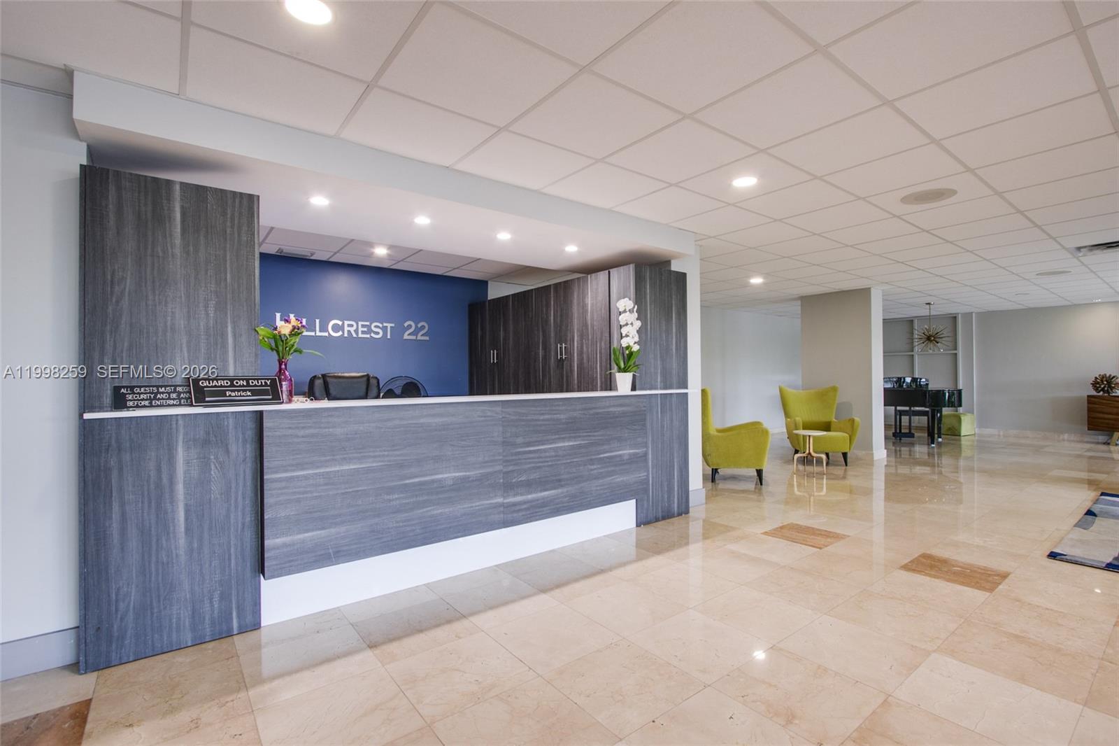 A reception desk with wood-look paneling sits in a lobby with tile floors and chairs — 4350 Hillcrest Dr # 303, Hollywood FL 33021, HOLLYWOOD, FL