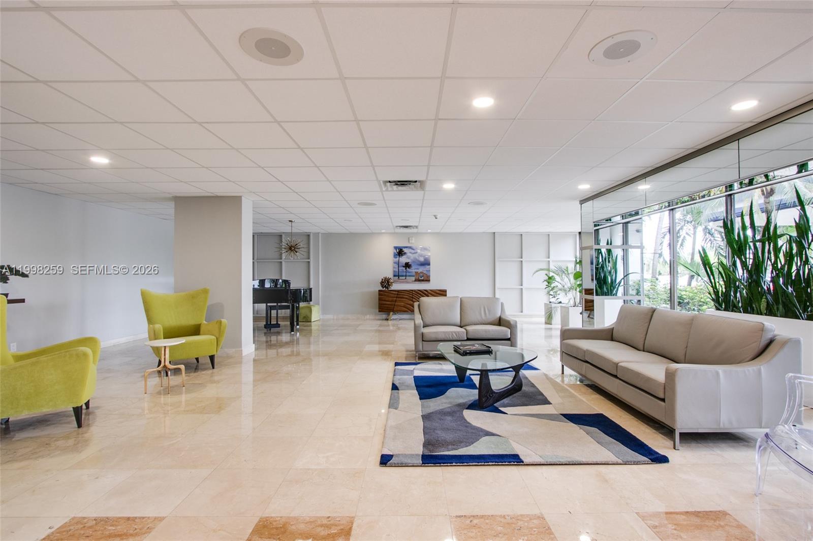 A spacious lobby features tile floors, two seating areas, a piano, and floor-to-ceiling windows — 4350 Hillcrest Dr # 303, Hollywood FL 33021, HOLLYWOOD, FL