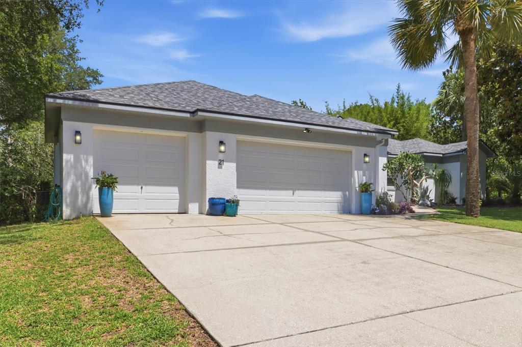 A white house exterior features a three-car garage, a concrete driveway, and a palm tree — 21 FIDDLEWOOD COURT, HOMOSASSA, FL