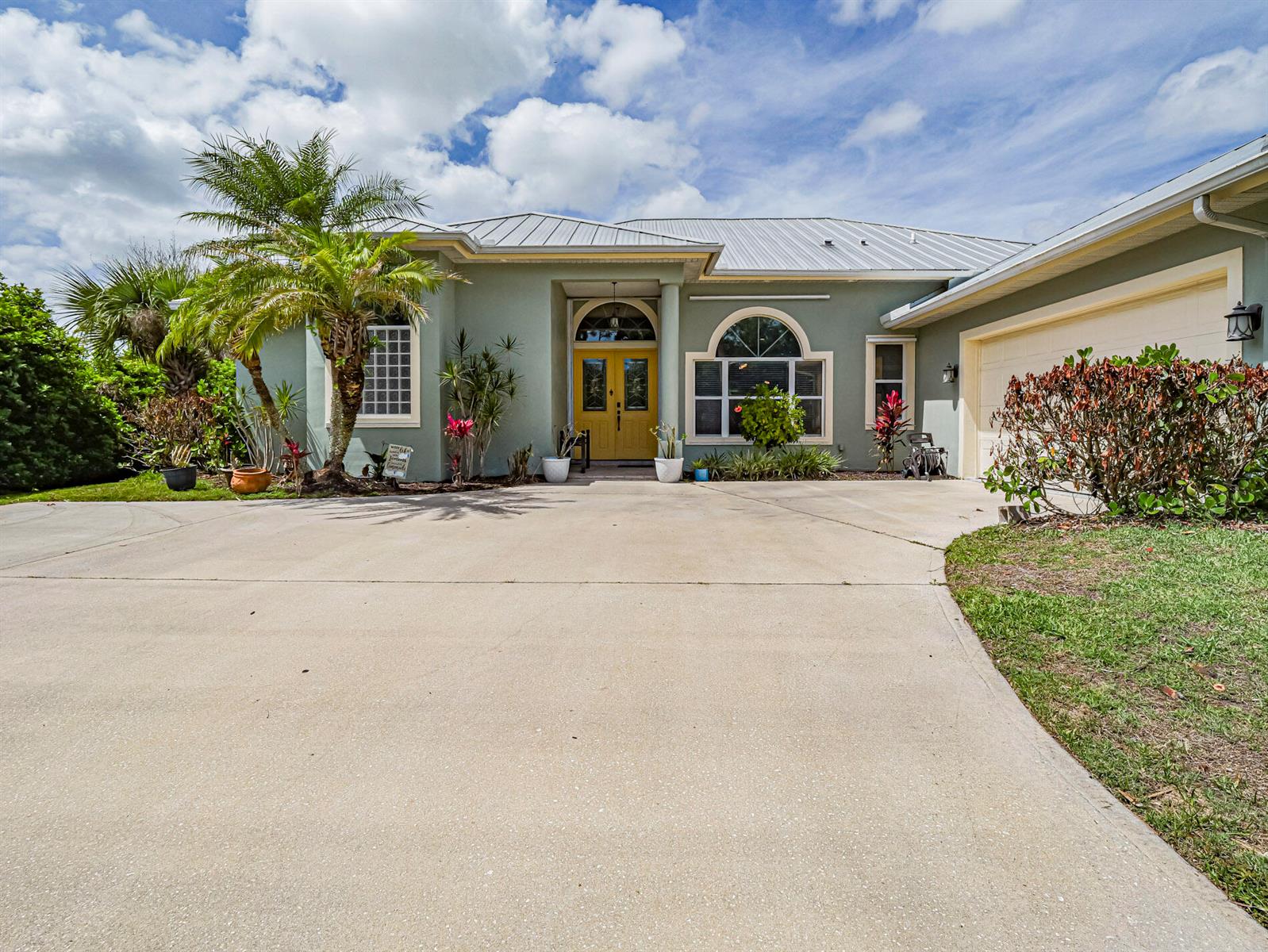 A single-story house with a light green exterior, yellow double front doors, and a concrete driveway — 6489 53rd Circle, Vero Beach FL 32967, VERO BEACH, FL
