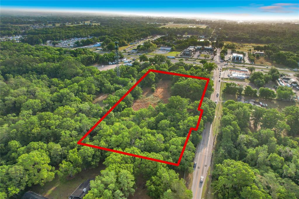 An aerial view shows a wooded, rectangular plot of land outlined in red along a road — 1301 DUFF ROAD, LAKELAND, FL