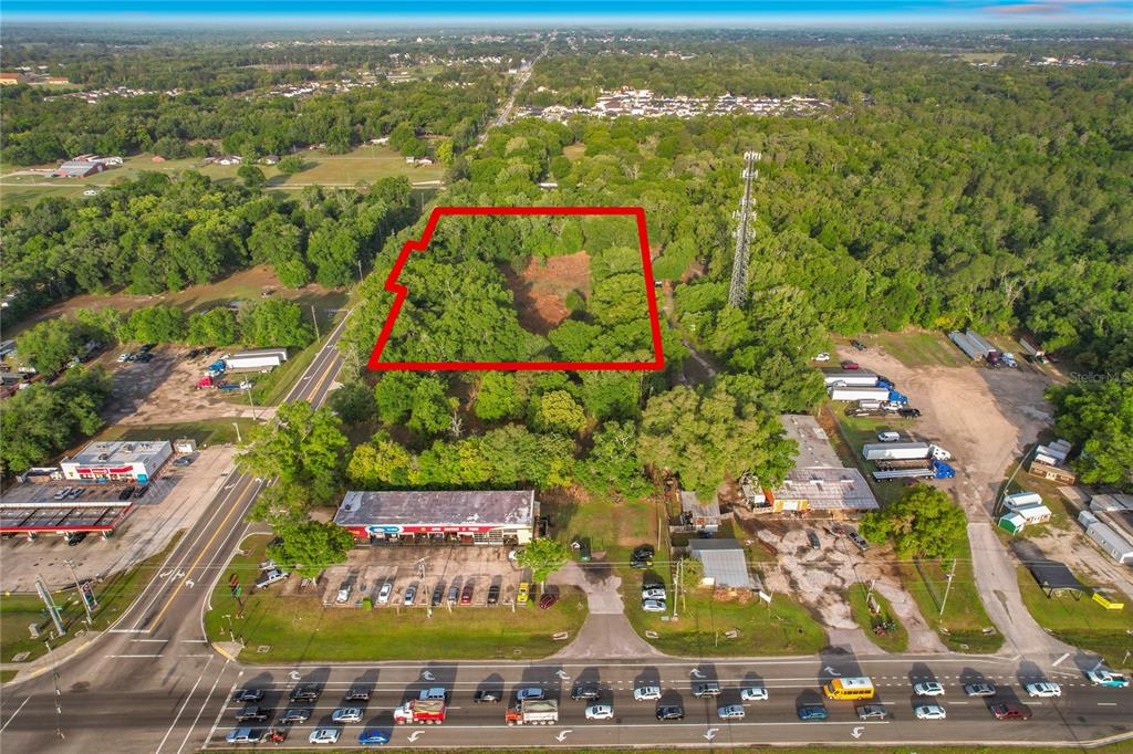 An aerial view shows a wooded lot outlined in red behind a commercial strip — 1301 DUFF ROAD, LAKELAND, FL