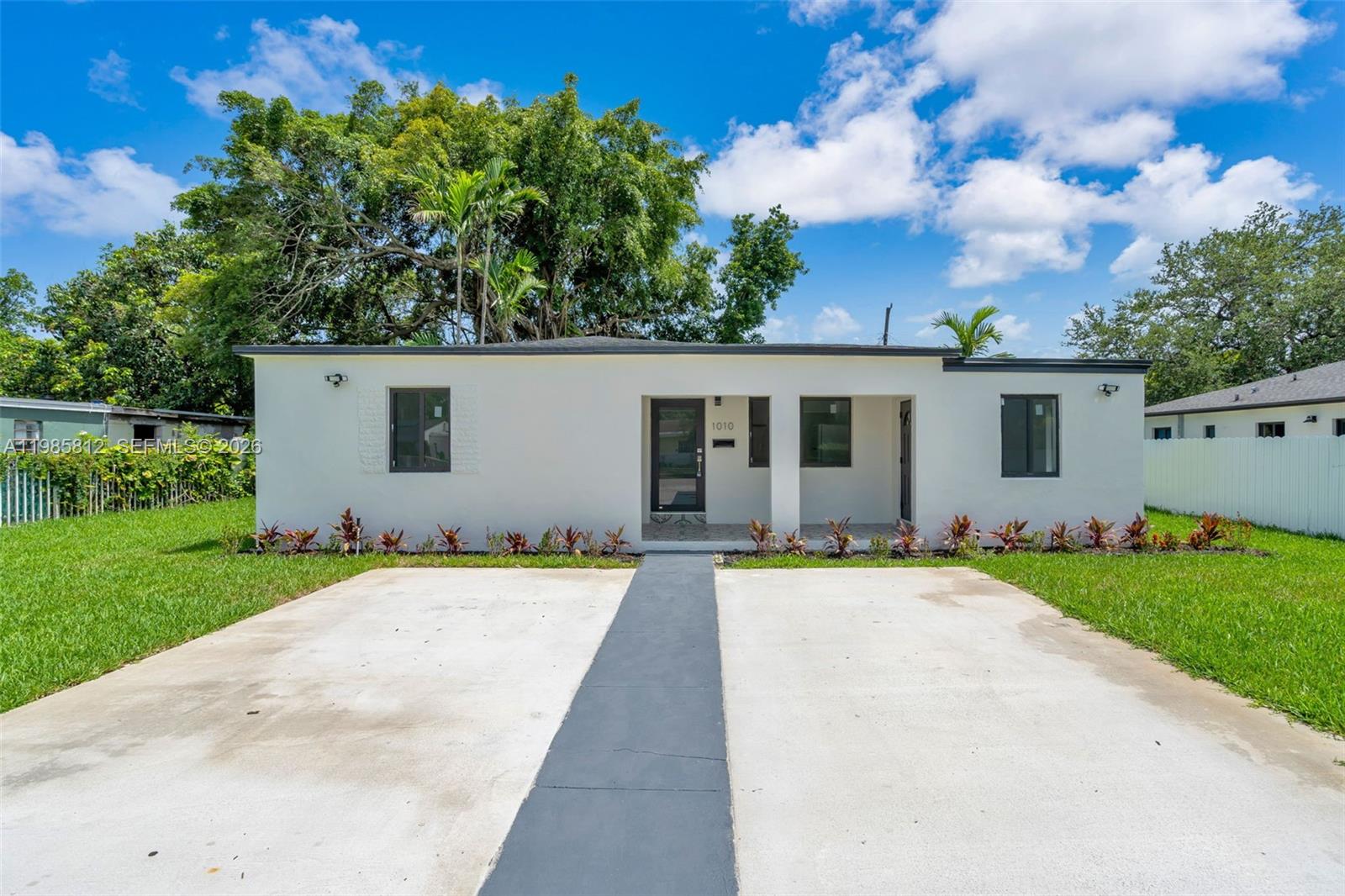 A single-story white house with a flat roof, a concrete driveway, and a front porch — 1010 NE 140th St, North Miami FL 33161, NORTH MIAMI, FL