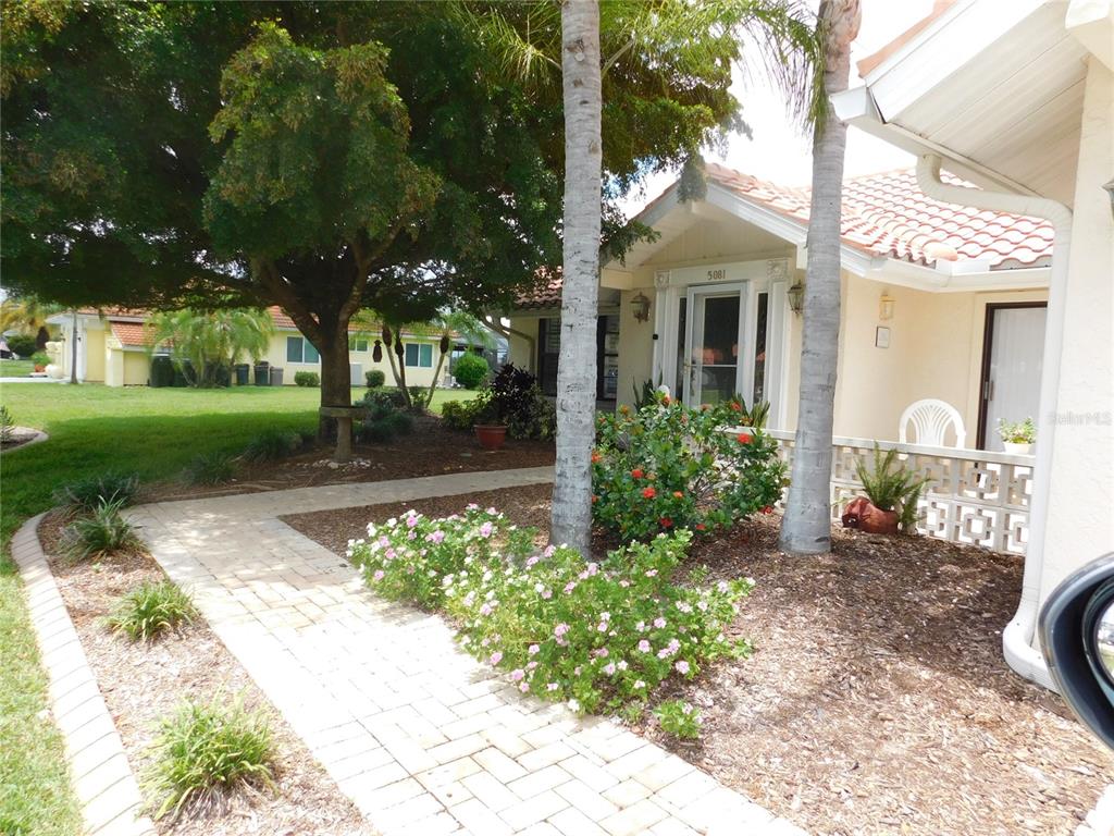 A paved walkway leads to the front entrance of a house with palm trees — 5081 KINGSLEY ROAD, NORTH PORT, FL