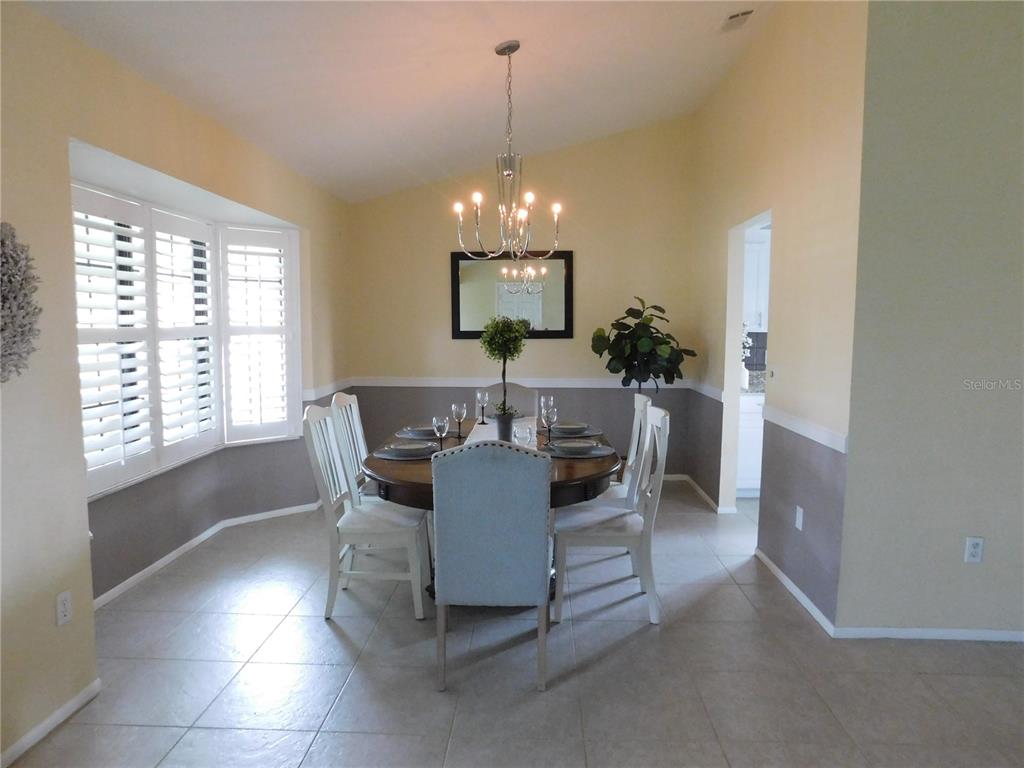 A dining room features a round wooden table, white chairs, and a chandelier — 5081 KINGSLEY ROAD, NORTH PORT, FL