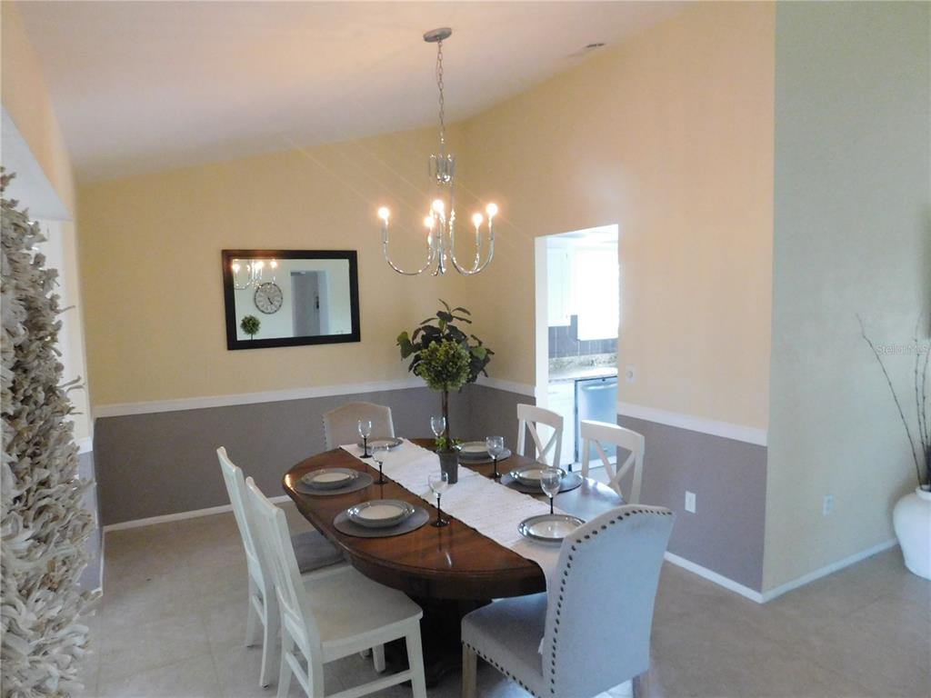 A dining room features a wooden table, chairs, a chandelier, and two-toned wall paint — 5081 KINGSLEY ROAD, NORTH PORT, FL