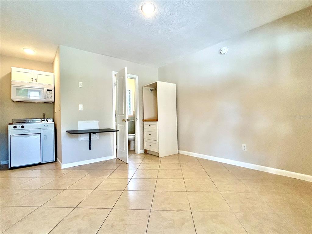 A small room features tile flooring, a kitchenette, a wall-mounted desk, and an open closet — 3618 N SCENIC HWY UNIT 2, LAKE WALES, FL