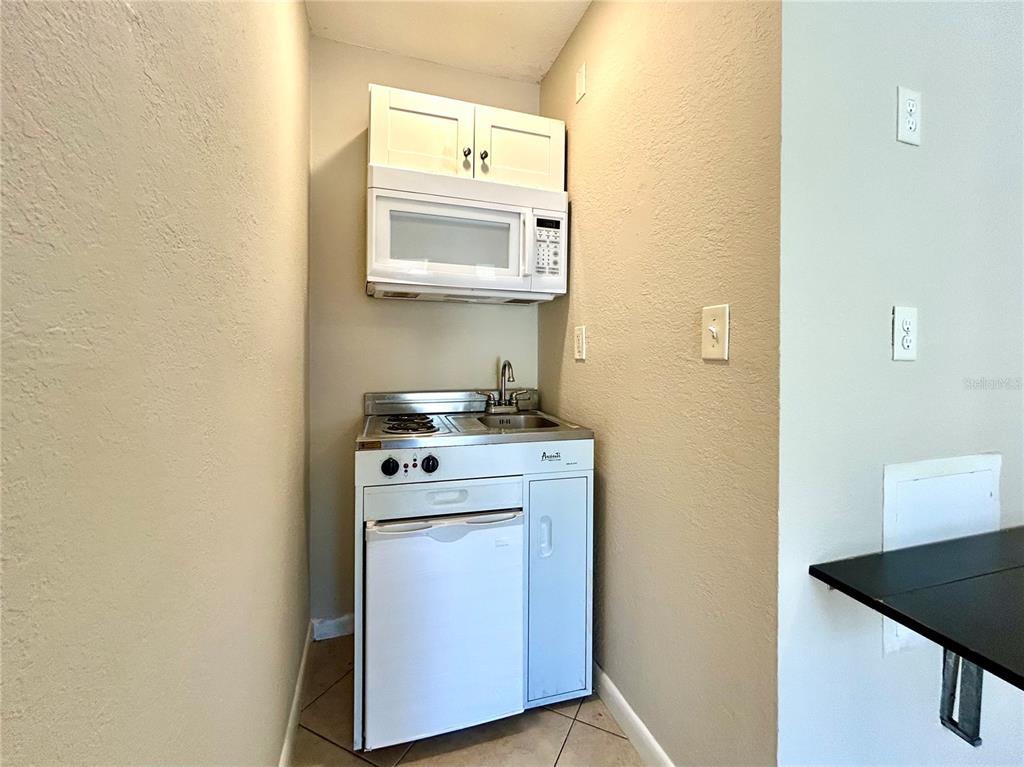 A small kitchenette features a compact stove, sink, under-counter refrigerator, and an over-the-range microwave — 3618 N SCENIC HWY UNIT 2, LAKE WALES, FL