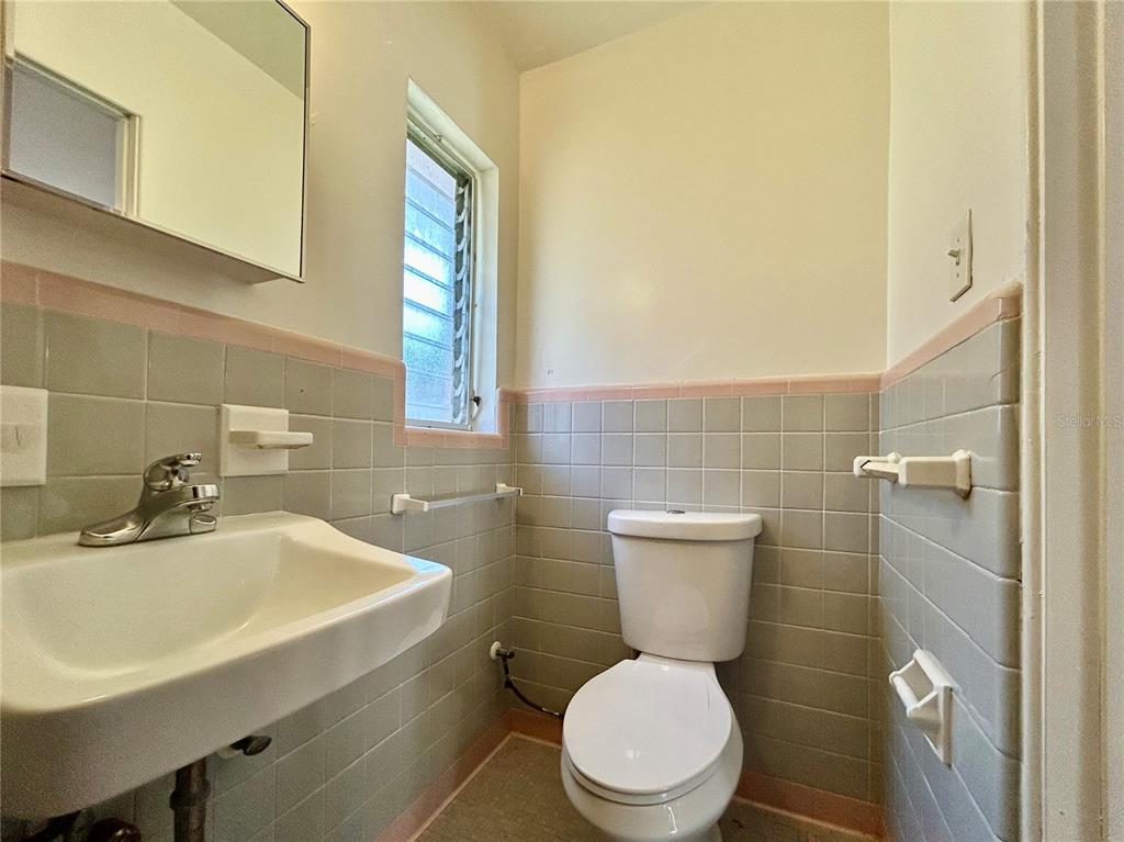 A small bathroom features gray square wall tiles with pink trim, a sink, and a toilet — 3618 N SCENIC HWY UNIT 2, LAKE WALES, FL