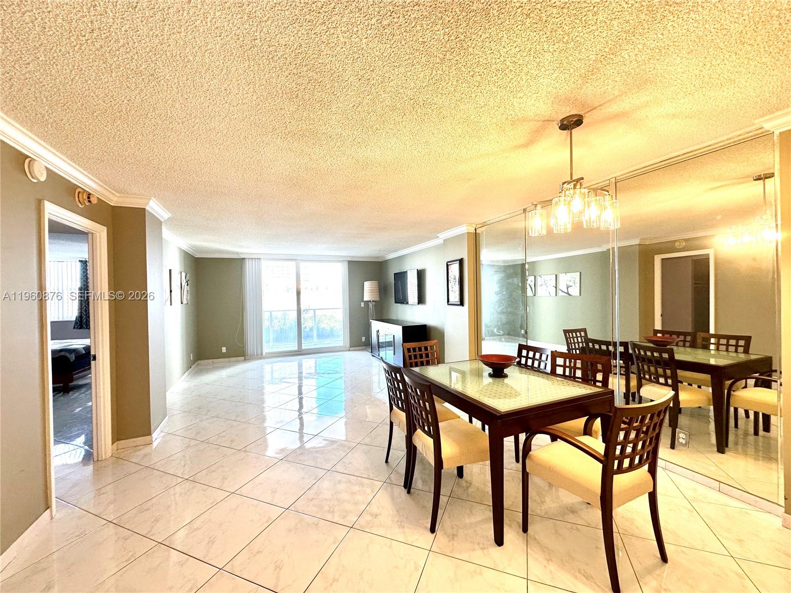 A dining area with a glass-topped table and tiled floors sits adjacent to a living space — 1904 S Ocean Dr # 701, Hallandale Beach FL 33009, HALLANDALE BEACH, FL