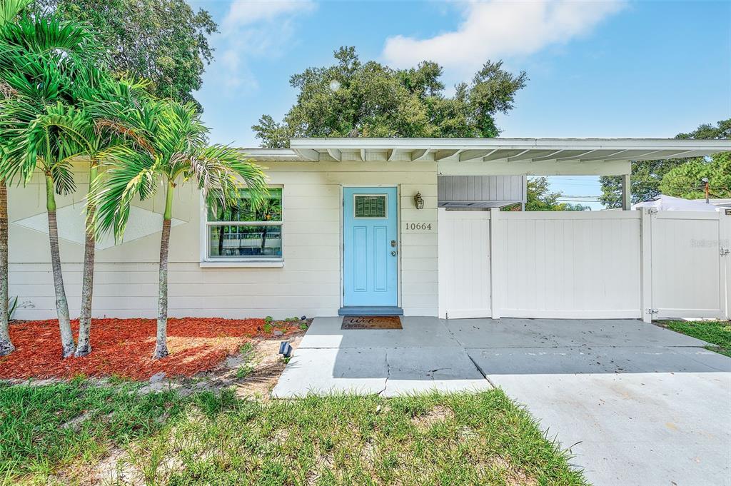 A single-story house exterior features a light blue front door, a carport, and palm trees — 10664 STARKEY ROAD, SEMINOLE, FL