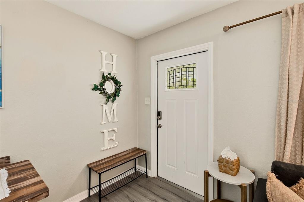 An entryway features a white door, a wooden bench, and a vertical "HOME" wall sign — 10664 STARKEY ROAD, SEMINOLE, FL
