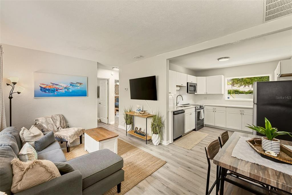 An open-concept living room and kitchen featuring light wood flooring and white cabinetry — 10664 STARKEY ROAD, SEMINOLE, FL