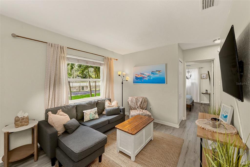 A living room features a grey sectional sofa, a wooden coffee table, and a wall-mounted television — 10664 STARKEY ROAD, SEMINOLE, FL