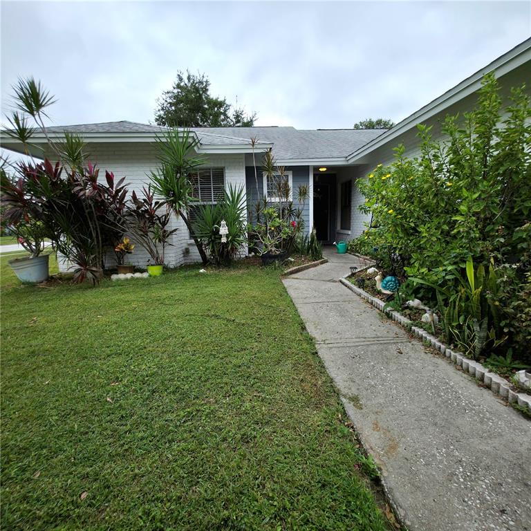 A single-story house with a white brick facade, a concrete walkway, and lush landscaping — 13202 PINE CREEK CIRCLE, RIVERVIEW, FL