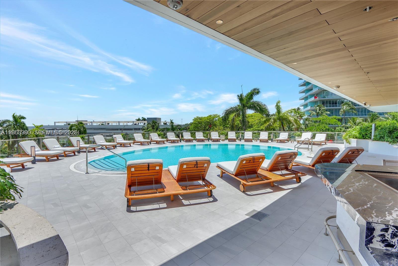 A swimming pool surrounded by lounge chairs on a tiled patio under a covered terrace — 2655 S Bayshore Dr # 706, Miami FL 33133, MIAMI, FL