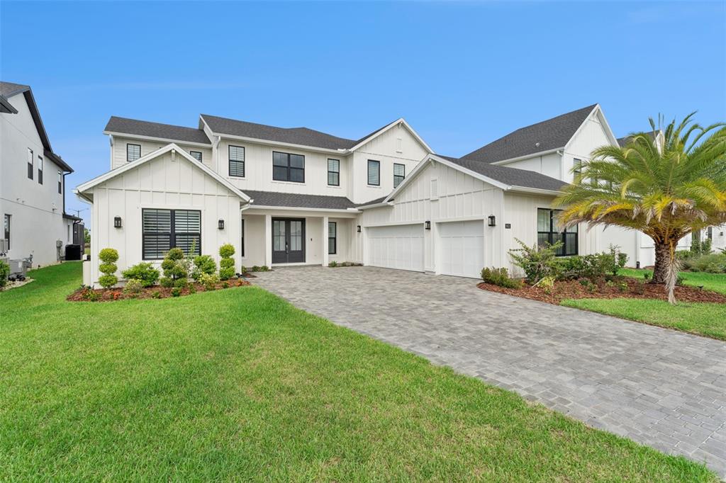 A two-story white farmhouse with a paved driveway, attached garage, and a palm tree — 9652 ENGLISH LAUREL COURT, ORLANDO, FL