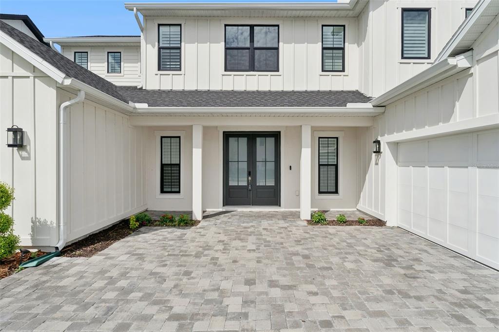 A white modern farmhouse exterior features a paved driveway, double front doors, and dark-framed windows — 9652 ENGLISH LAUREL COURT, ORLANDO, FL