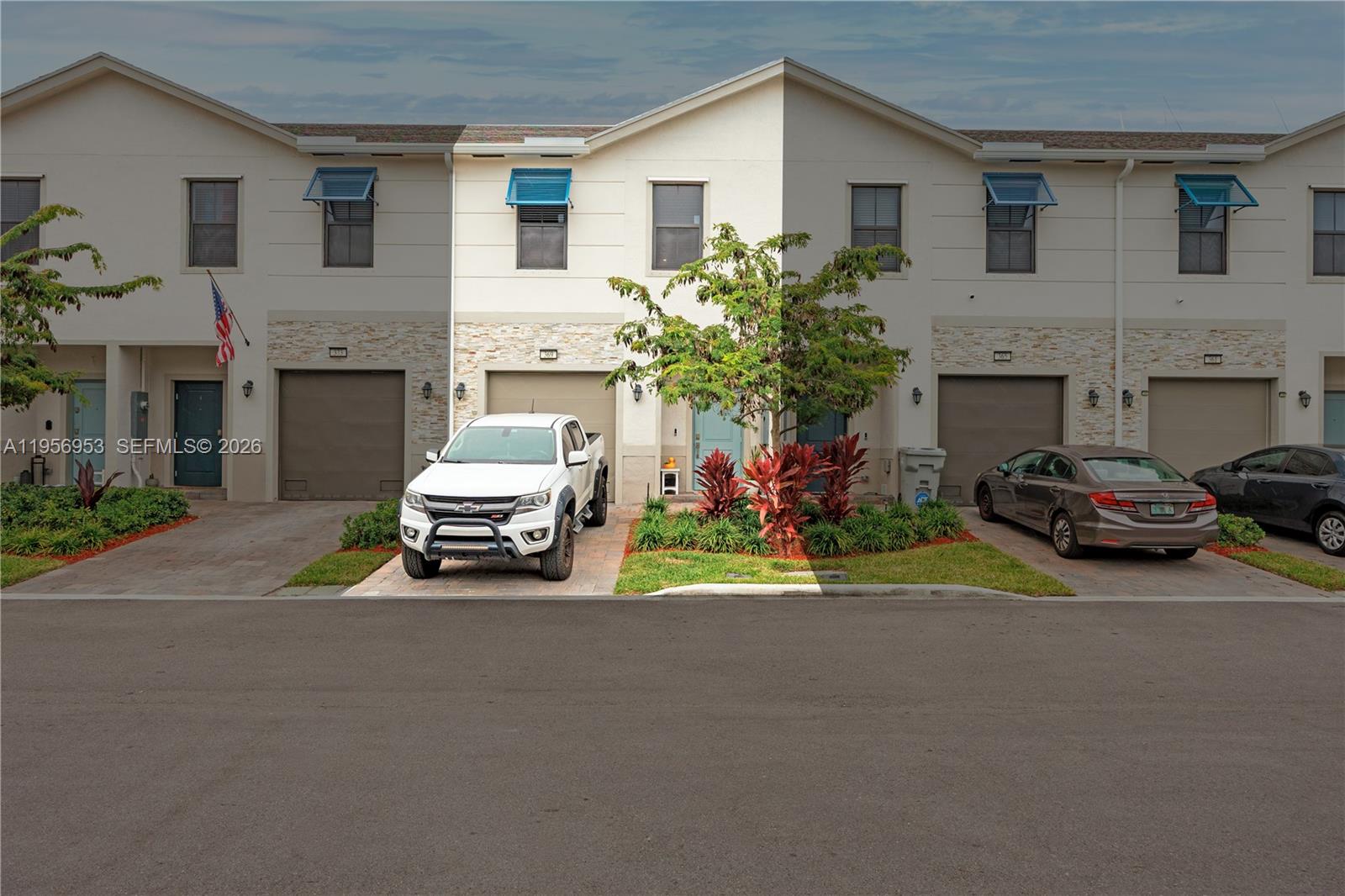 A row of two-story townhouses with attached garages, paved driveways, and small front gardens — 369 NW 8th Ct, Pompano Beach FL 33060, POMPANO BEACH, FL