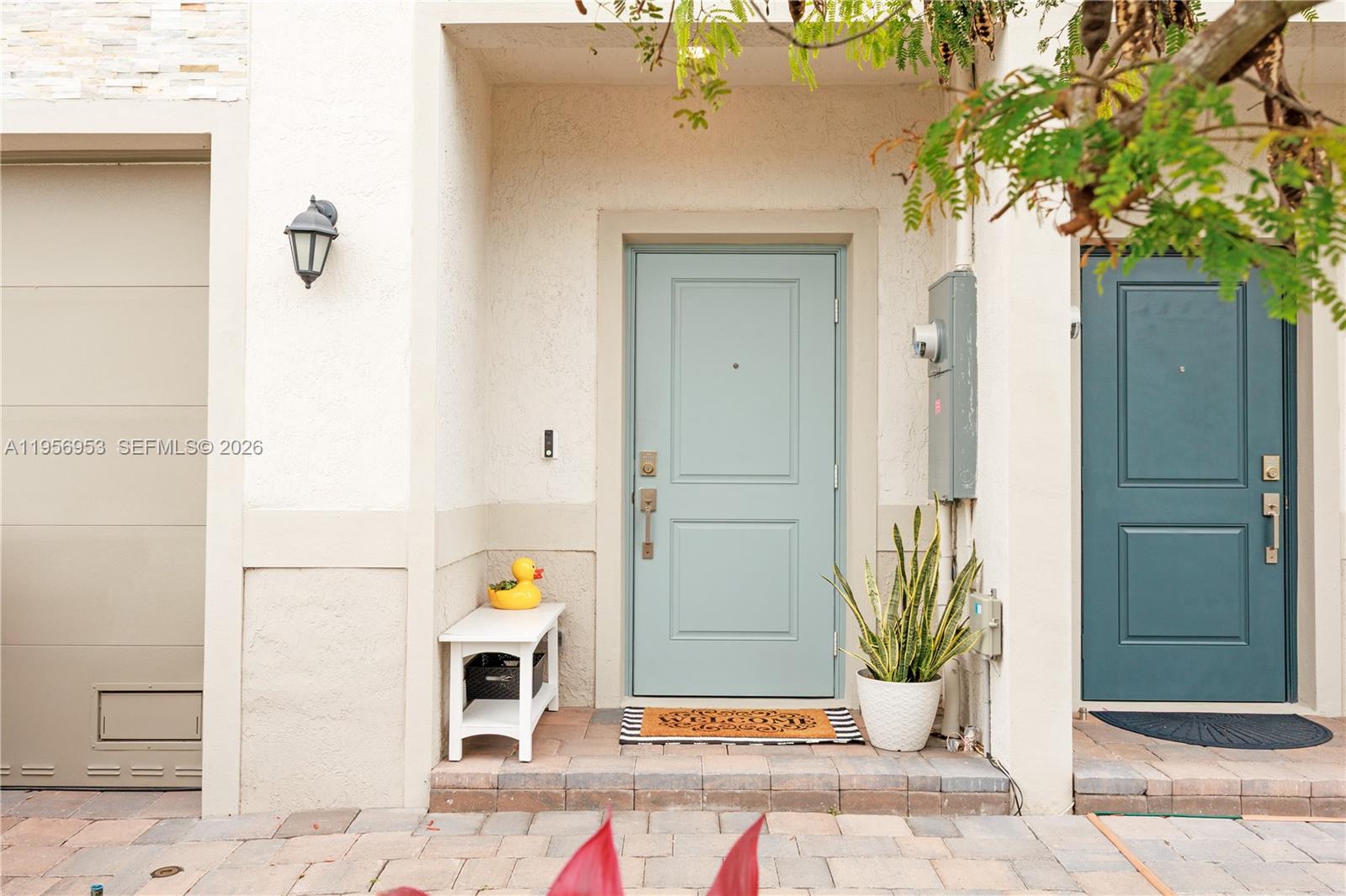 A light blue front door sits between a white bench and a potted snake plant — 369 NW 8th Ct, Pompano Beach FL 33060, POMPANO BEACH, FL