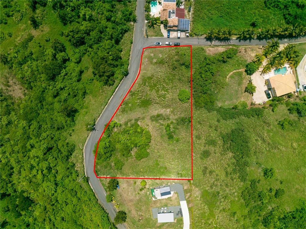 An aerial view shows a vacant, trapezoidal plot of land bordered by a paved road — Barrio Mameyes LINDO MAR II Lote 14, RIO GRANDE, PR