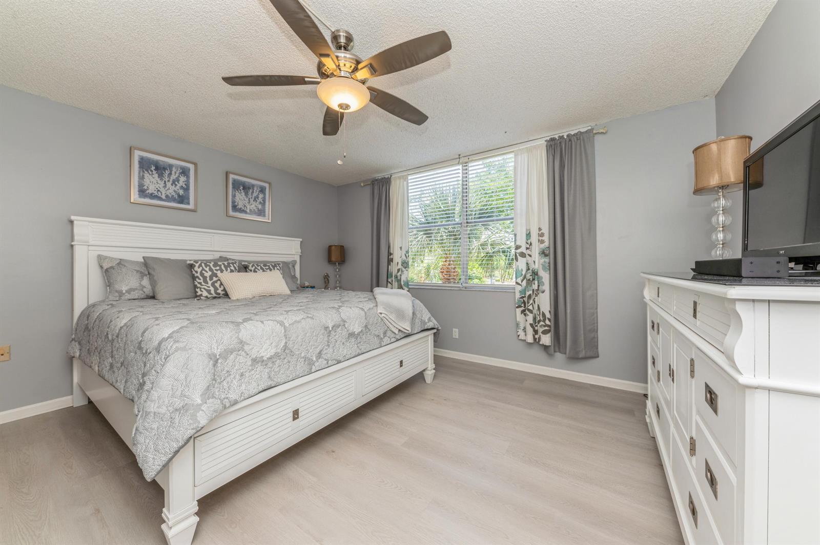 A bedroom with light gray walls, white furniture, a ceiling fan, and a window with curtains — 14527 Bonaire Boulevard # 303, Delray Beach FL 33446, DELRAY BEACH, FL