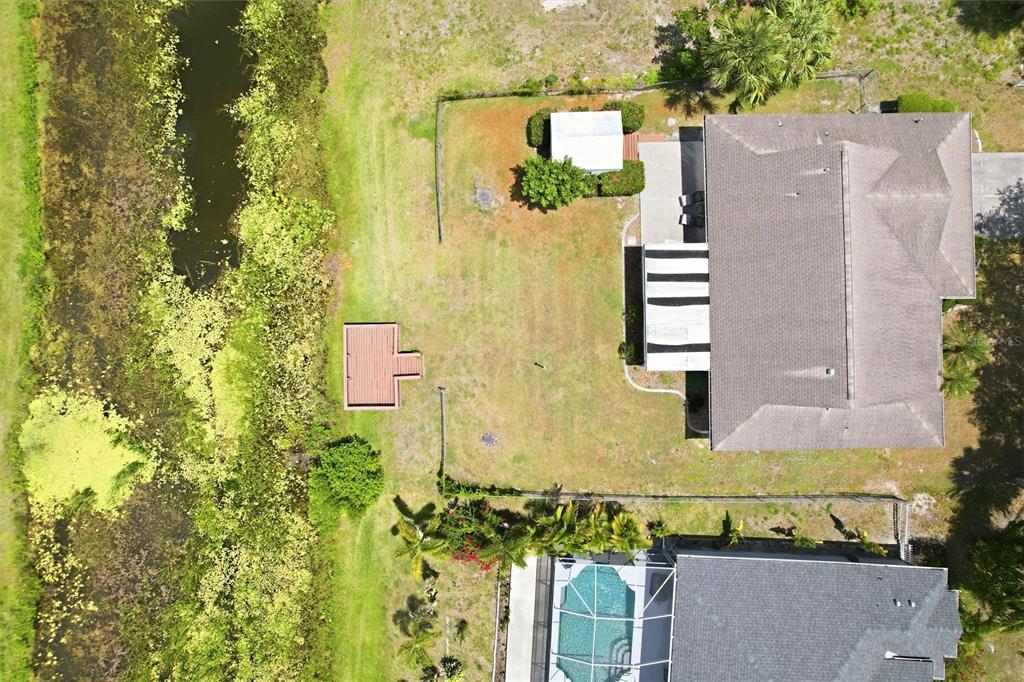 An aerial view shows a house with a backyard, a small shed, and a canal — 1299 TRIPOLI STREET, NORTH PORT, FL