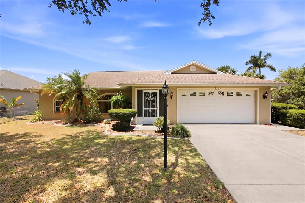 A single-story house with a beige exterior, a two-car garage, and a front lawn — 1299 TRIPOLI STREET, NORTH PORT, FL