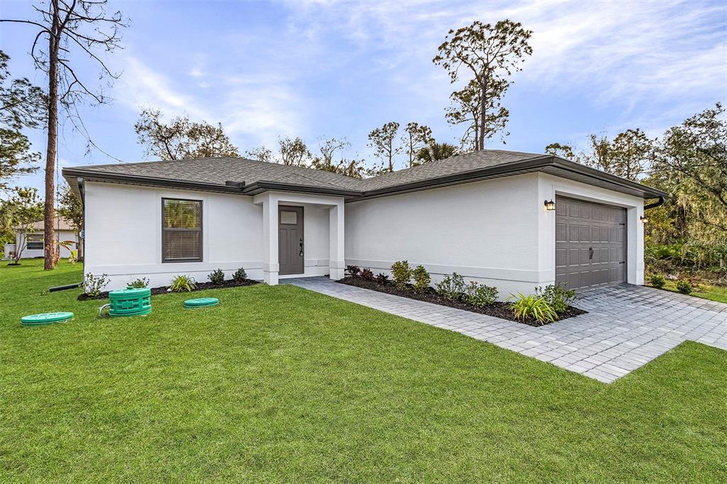 A white single-story house with a gray garage door and a paved walkway — 3453 WORTHINGTON AVENUE, NORTH PORT, FL