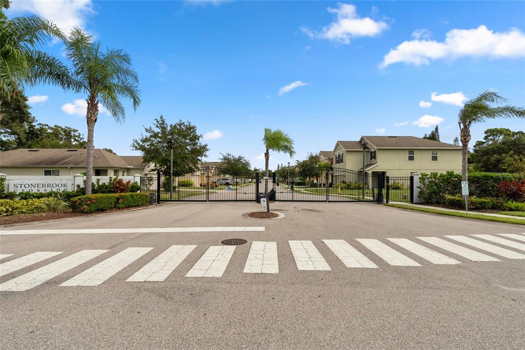 A gated entrance with a crosswalk leads into a residential community named Stonebrook Crossing — 5946 81ST AVENUE N, PINELLAS PARK, FL
