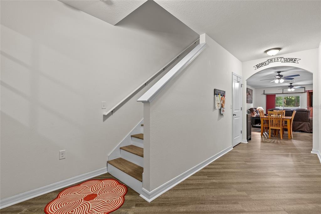 A staircase with wood treads and white risers sits beside a hallway leading to a dining area — 5946 81ST AVENUE N, PINELLAS PARK, FL