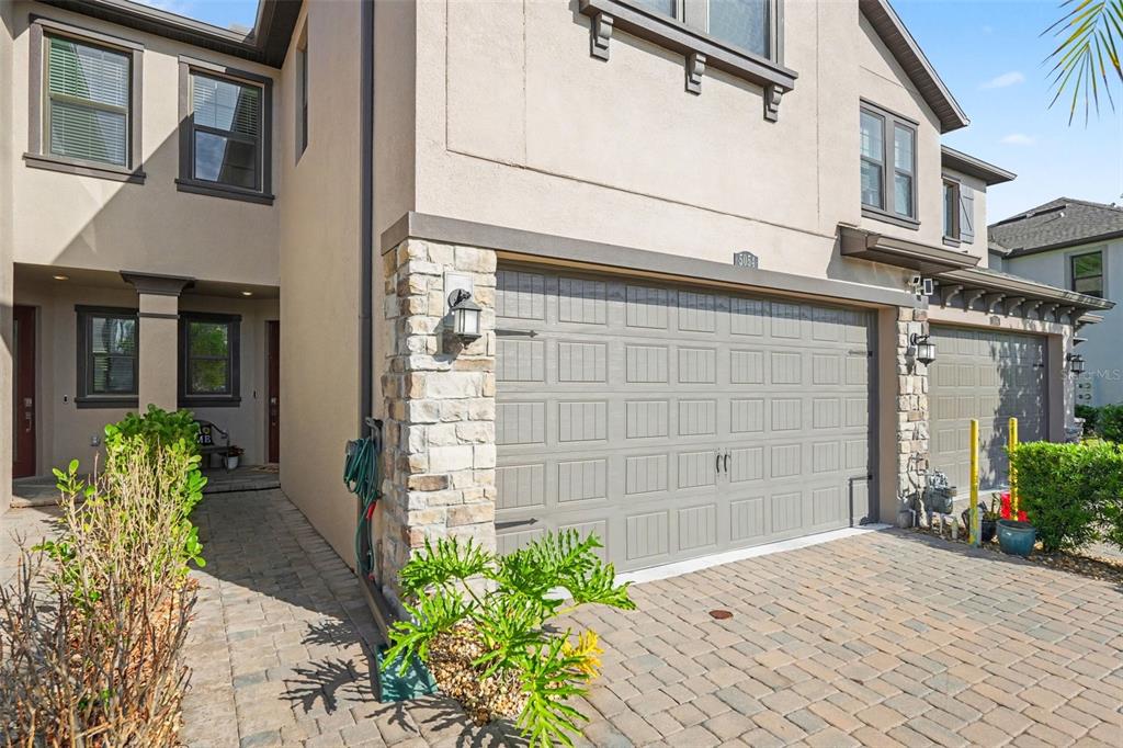 A two-story house exterior features a stone-accented garage, a paved driveway, and a side entrance — 5054 SAN MARTINO DRIVE, WESLEY CHAPEL, FL