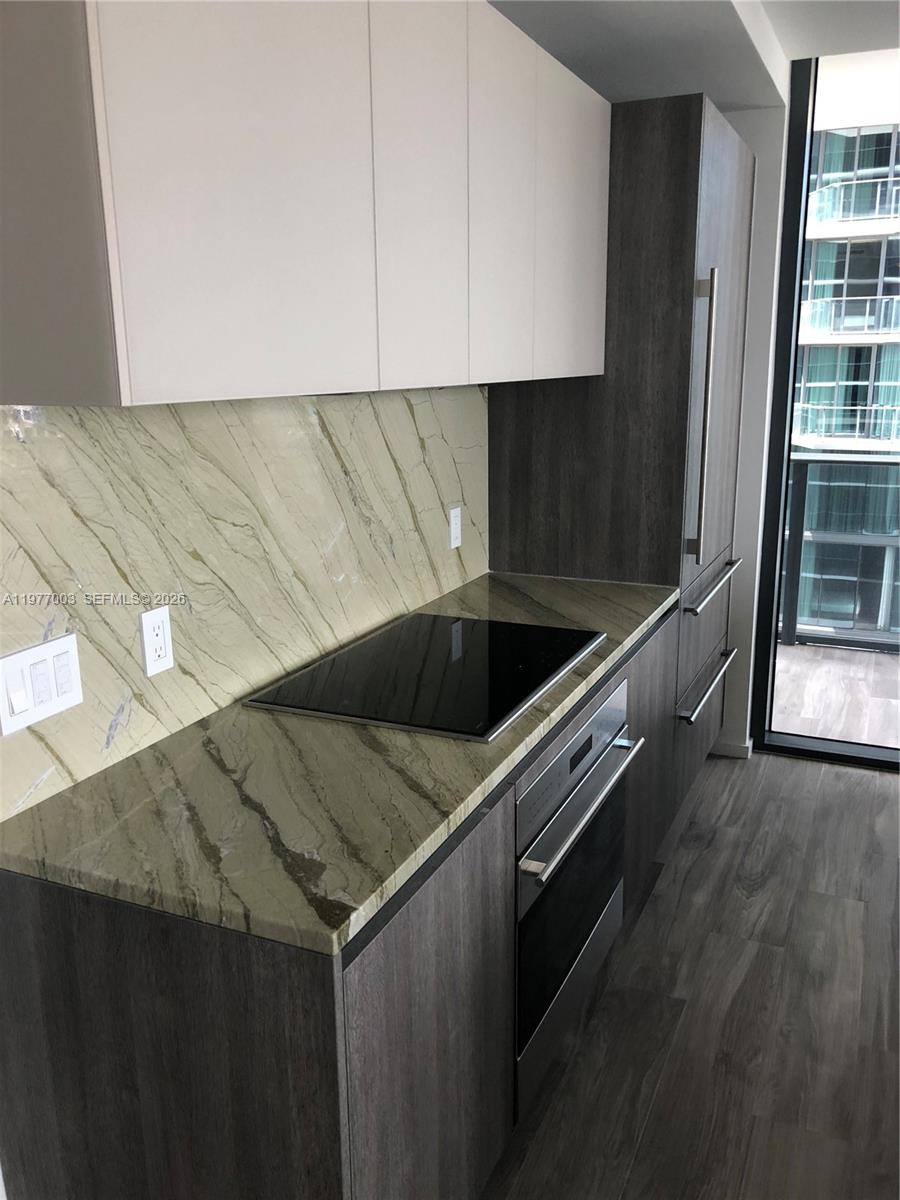 A modern kitchen features dark wood cabinetry, white upper cabinets, and a green marble backsplash — 801 S Miami Ave # 1705, Miami FL 33131, MIAMI, FL