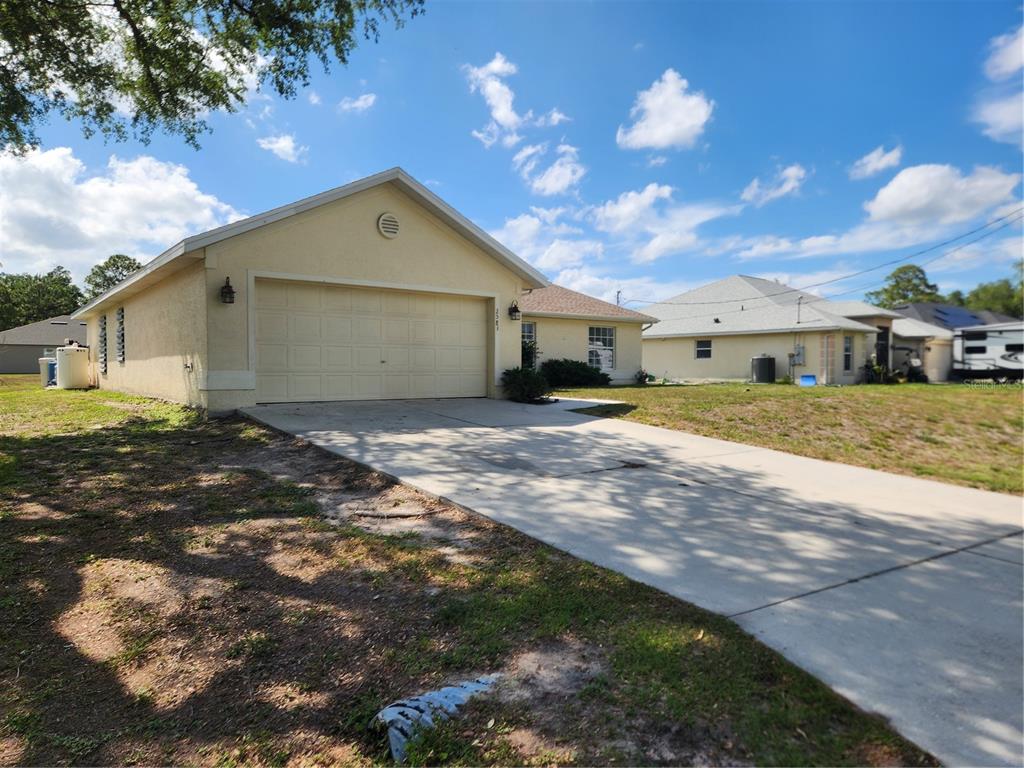 A single-story house with a beige stucco exterior, a two-car garage, and a concrete driveway — 2583 WILBURN TERRACE, NORTH PORT, FL