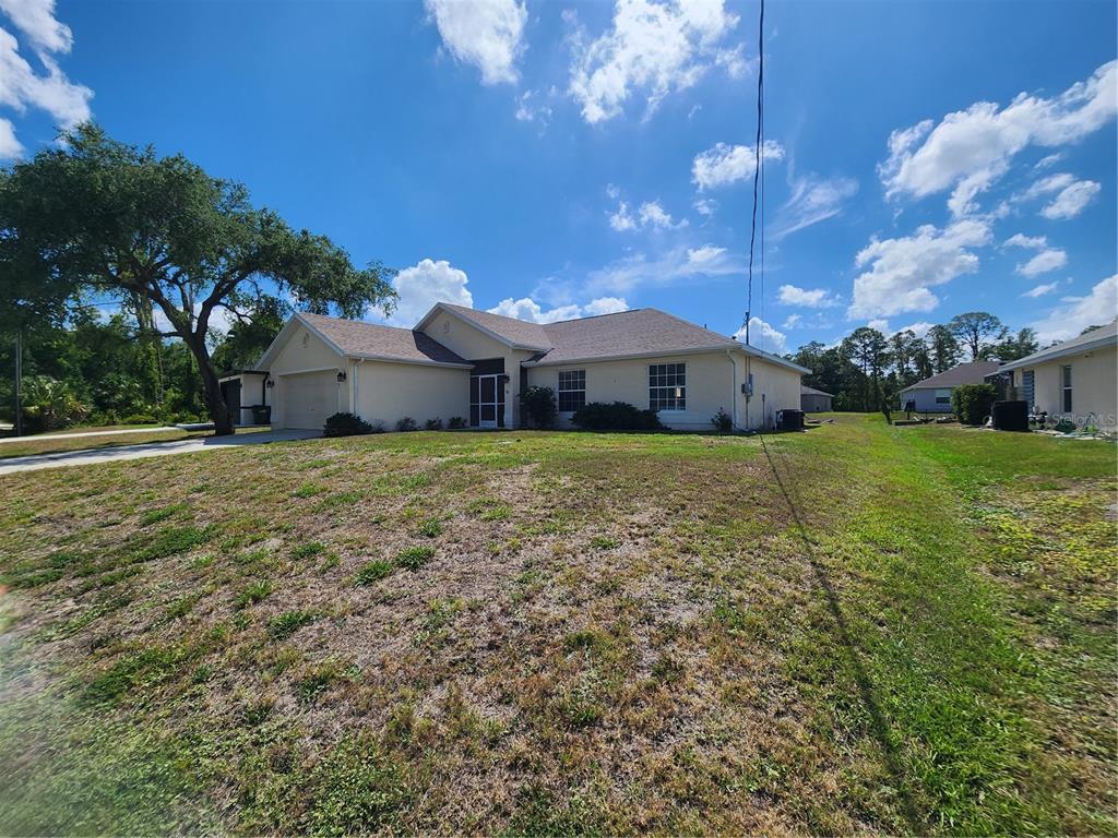 A single-story house with a beige exterior, a two-car garage, and a large front yard — 2583 WILBURN TERRACE, NORTH PORT, FL