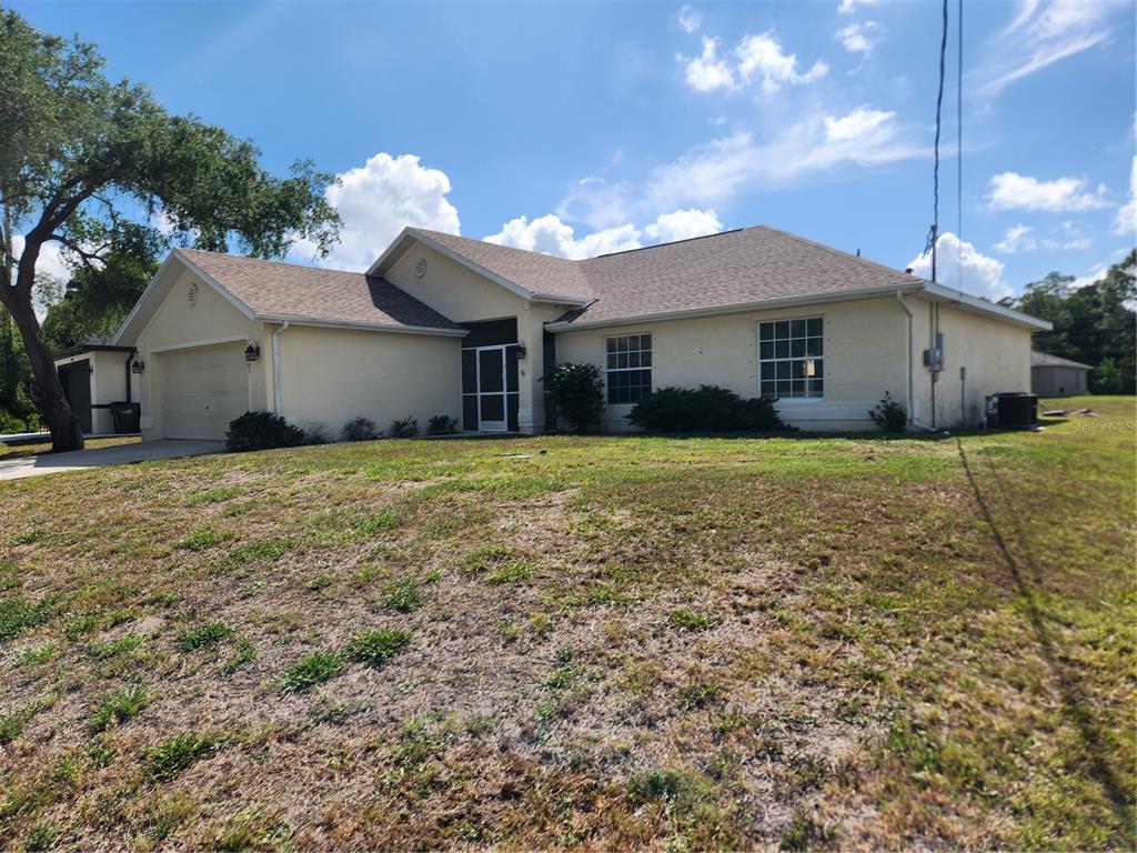 A single-story house with a beige stucco exterior, a two-car garage, and a grassy yard — 2583 WILBURN TERRACE, NORTH PORT, FL