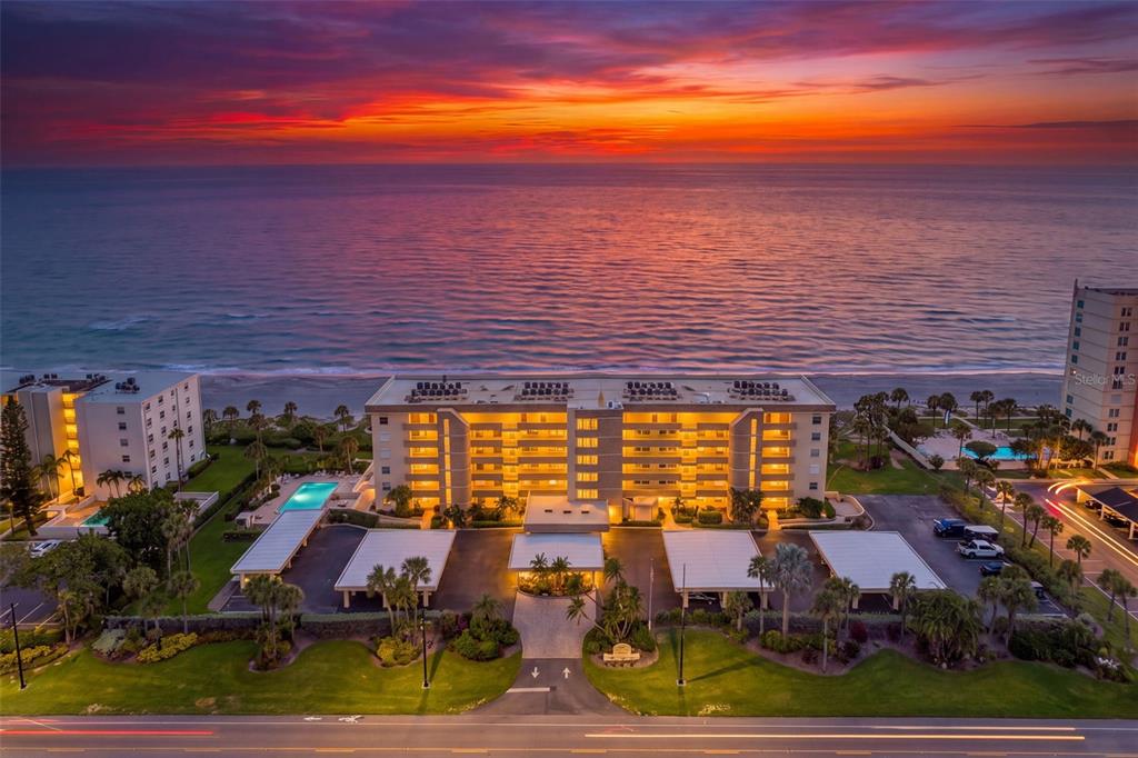 An aerial view of a multi-story beachfront apartment building at sunset with a parking lot — 4325 GULF OF MEXICO DRIVE UNIT 402, LONGBOAT KEY, FL