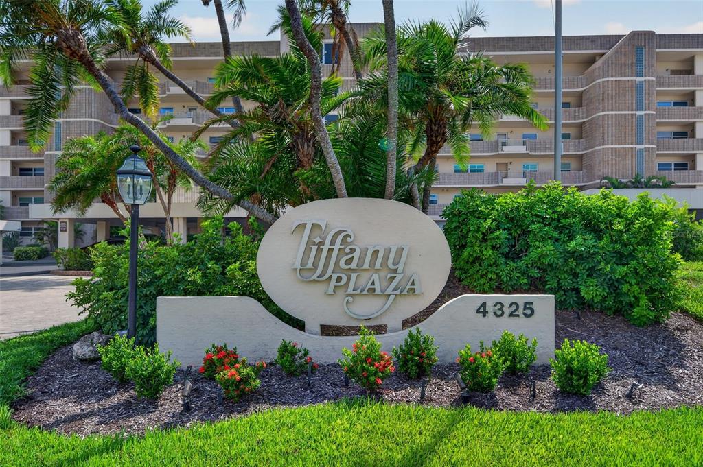 A sign for Tiffany Plaza stands in front of a multi-story apartment building with palm trees — 4325 GULF OF MEXICO DRIVE UNIT 402, LONGBOAT KEY, FL