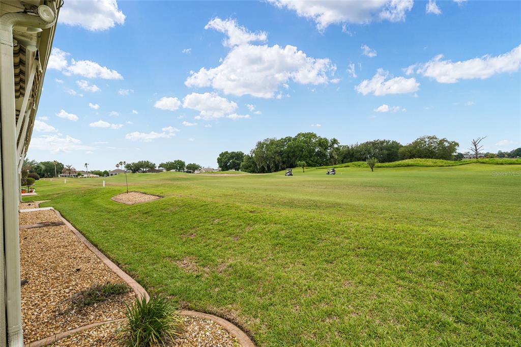 A view from a patio overlooking a grassy golf course under a blue sky — 13500 SE 97TH TERRACE ROAD, SUMMERFIELD, FL