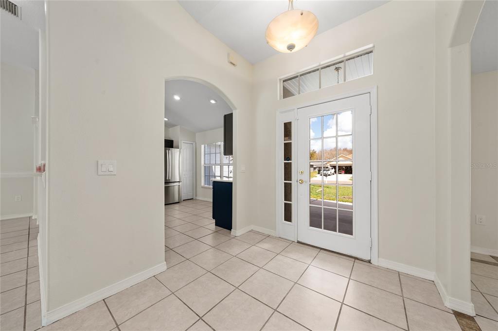 An entryway with light tile flooring, a white front door, and an arched kitchen opening — 3586 YELLOW BIRD COURT, ST CLOUD, FL