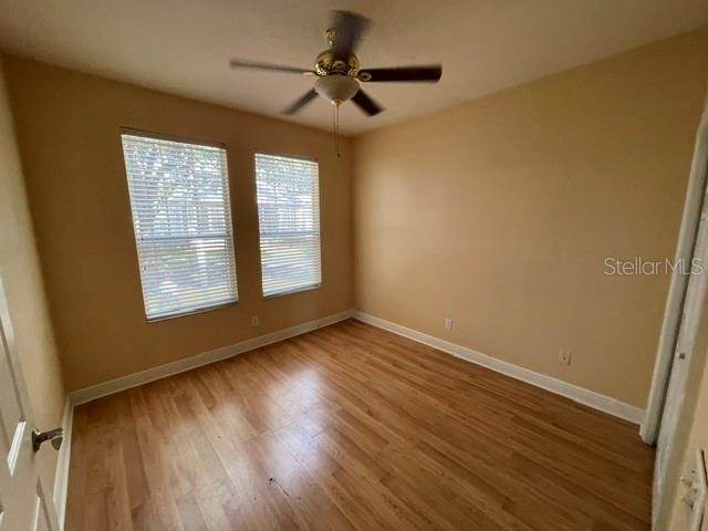An empty bedroom features light-colored walls, wood-look flooring, two windows, and a ceiling fan — 6344 BIRMINGHAM AVENUE, ZEPHYRHILLS, FL