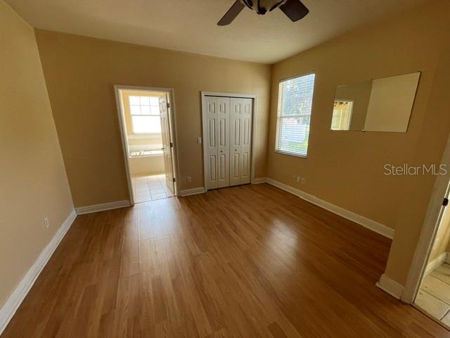 A bedroom with light wood-look flooring, a white closet, and a doorway leading to a bathroom — 6344 BIRMINGHAM AVENUE, ZEPHYRHILLS, FL