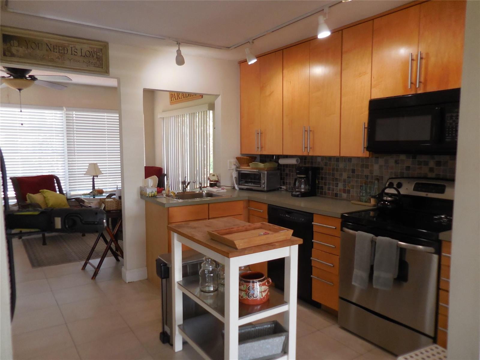 A kitchen with light wood cabinets, stainless steel appliances, and a small white kitchen island — 3050 NW 1st Avenue, Pompano Beach FL 33064, POMPANO BEACH, FL