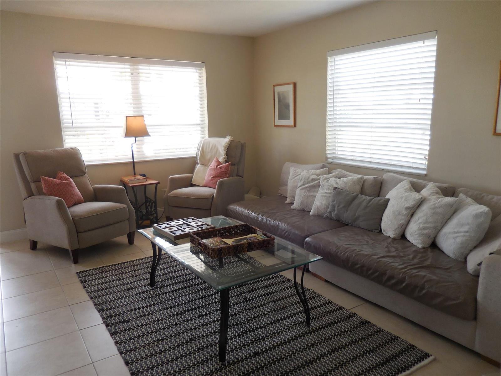 A living room features a brown sofa, two armchairs, a glass coffee table, and area rug — 3050 NW 1st Avenue, Pompano Beach FL 33064, POMPANO BEACH, FL