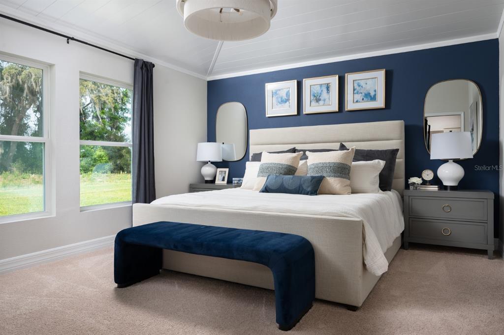 A bedroom features a navy accent wall, a beige upholstered bed, and a blue velvet bench — 6173 SW 97TH STREET, OCALA, FL