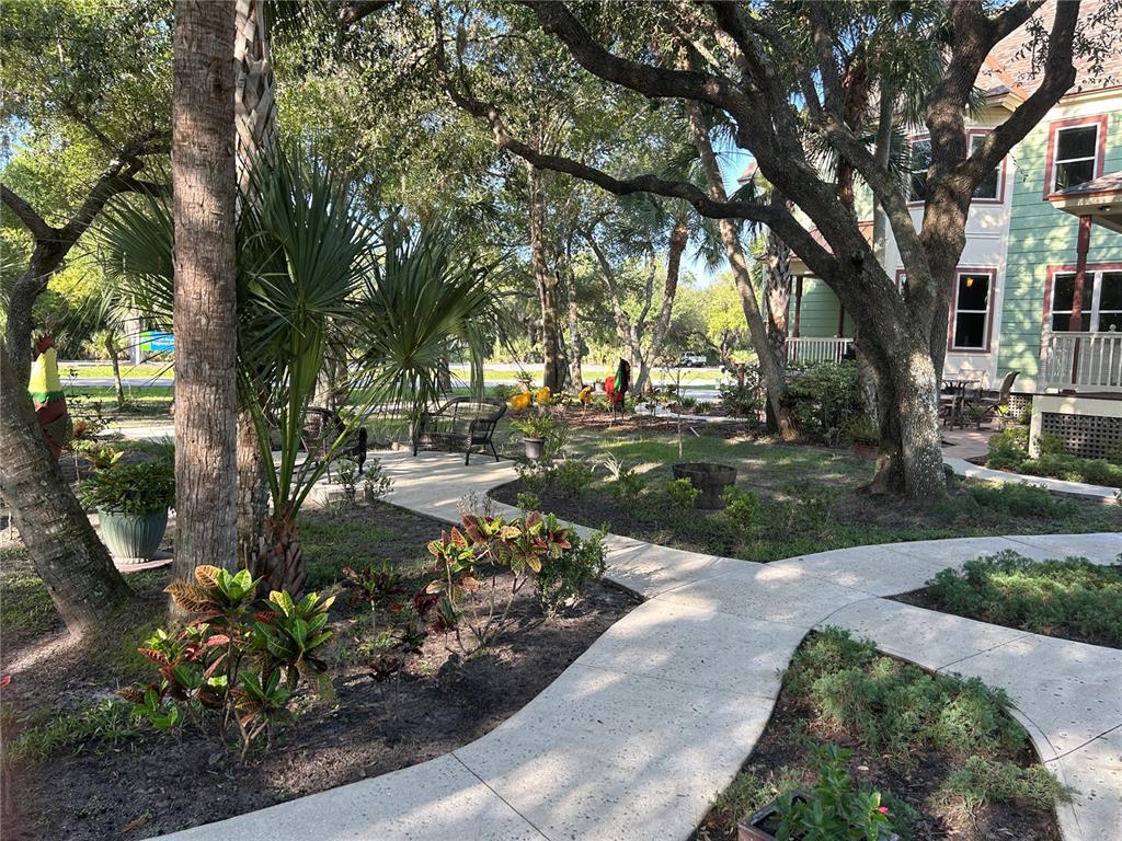 A concrete walkway winds through a landscaped yard with trees and a multi-story house — 23406 AGATHA AVENUE, PUNTA GORDA, FL