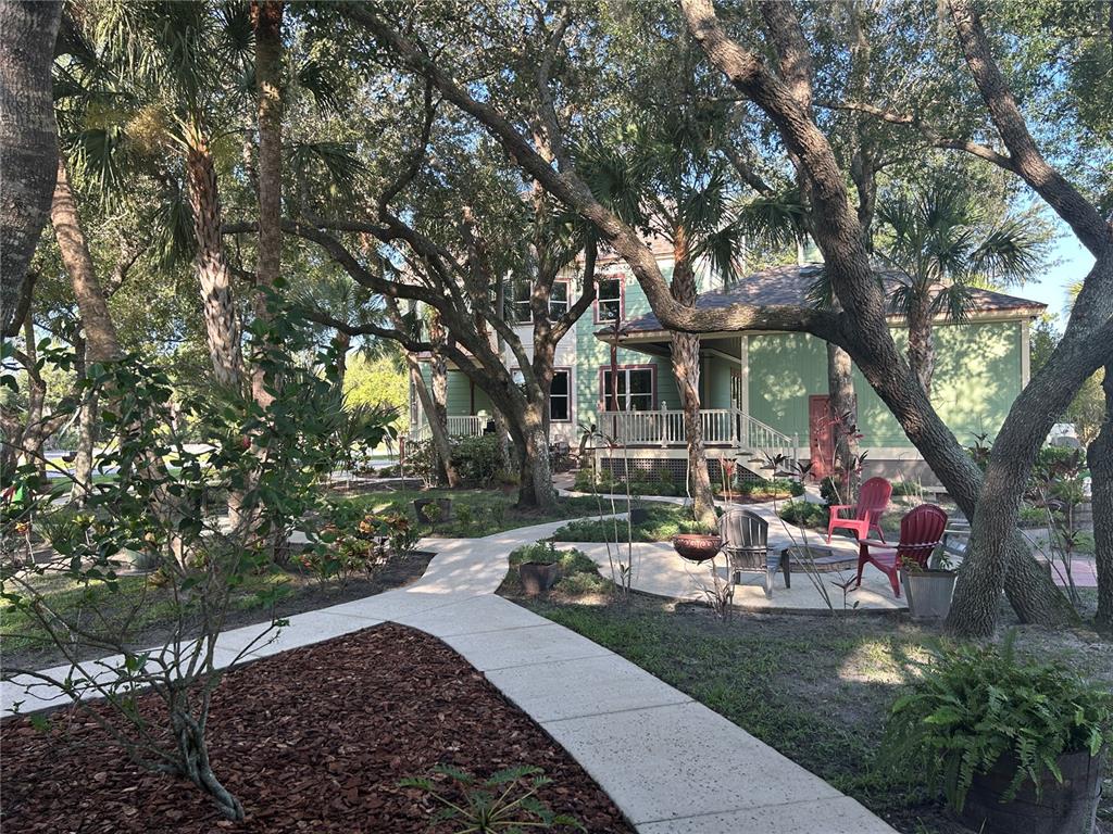 A light green house with a porch is surrounded by trees and a concrete walkway — 23406 AGATHA AVENUE, PUNTA GORDA, FL