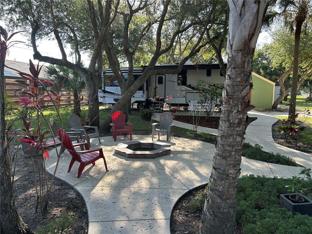 A concrete patio with a fire pit and chairs sits in front of a parked RV — 23406 AGATHA AVENUE, PUNTA GORDA, FL
