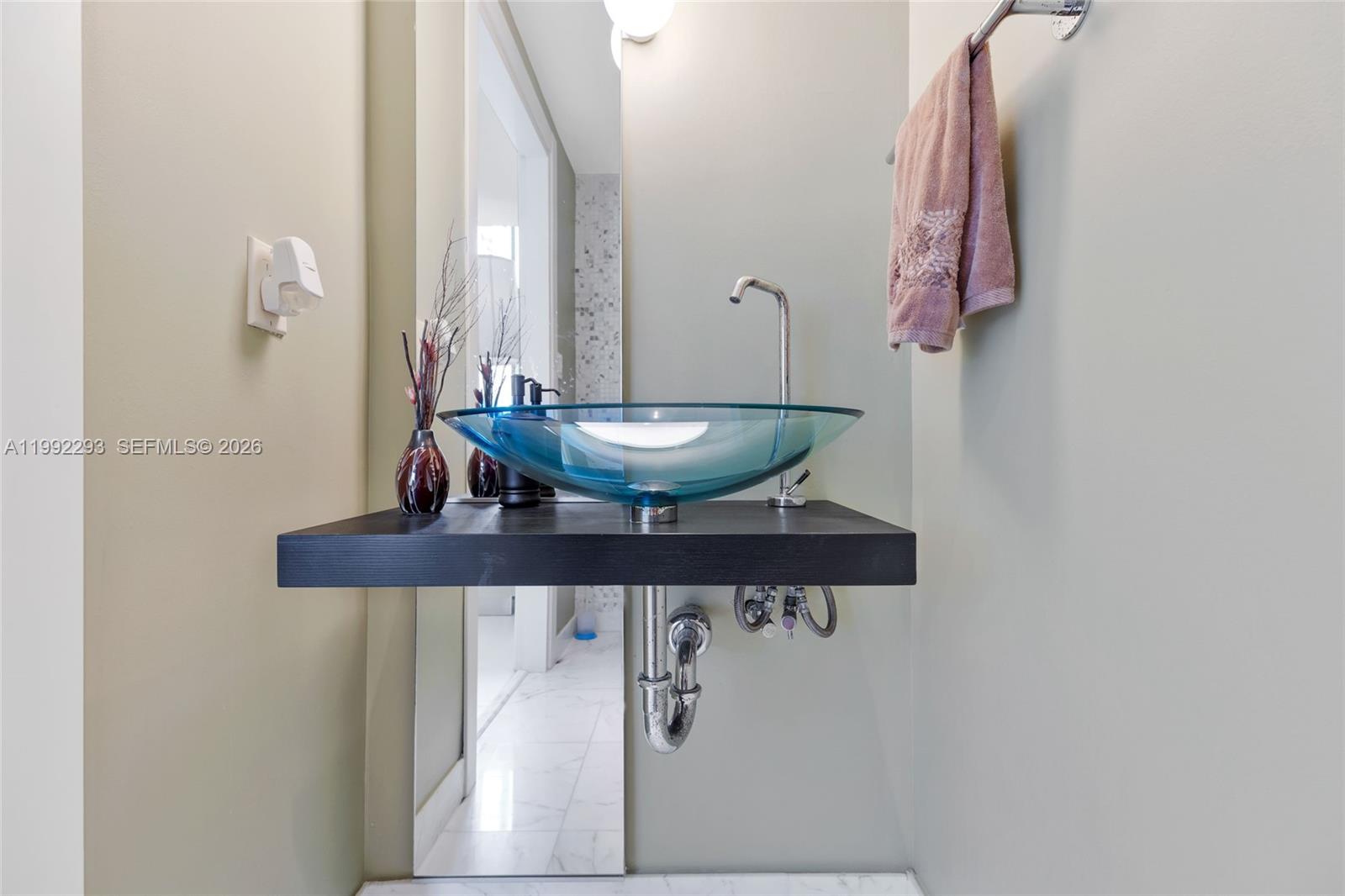 A bathroom features a blue glass vessel sink mounted on a floating black shelf — 200 Biscayne Boulevard Way # 504, Miami FL 33131, MIAMI, FL