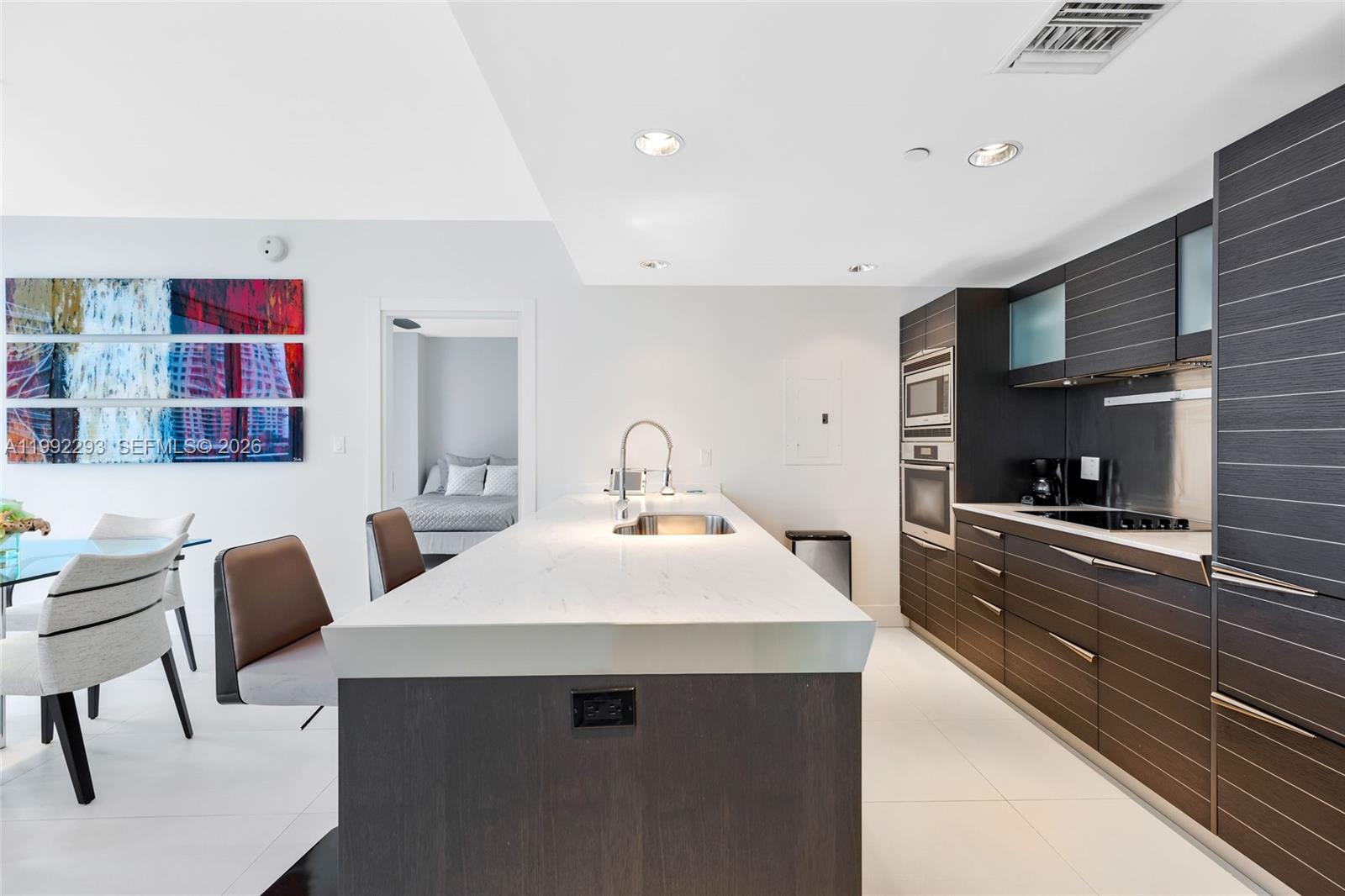 A modern kitchen features a white marble island, dark wood cabinetry, and stainless steel appliances — 200 Biscayne Boulevard Way # 504, Miami FL 33131, MIAMI, FL